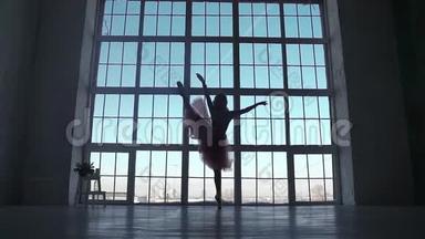 大窗户背景上芭蕾舞演员的剪影。 芭蕾舞演员穿着尖角鞋旋转。 剪影